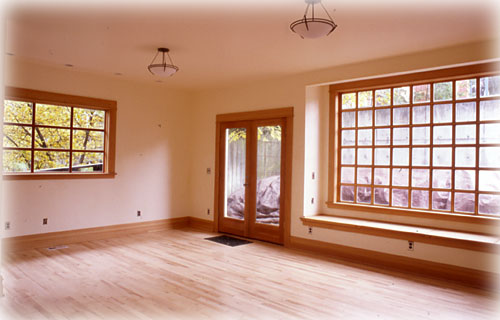 Open living room with hardwood, large window with recessed bench, and glass door to the patio