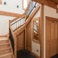 The entryway of a house with hardwood stairs, dark concrete floors, and warm wood trim.