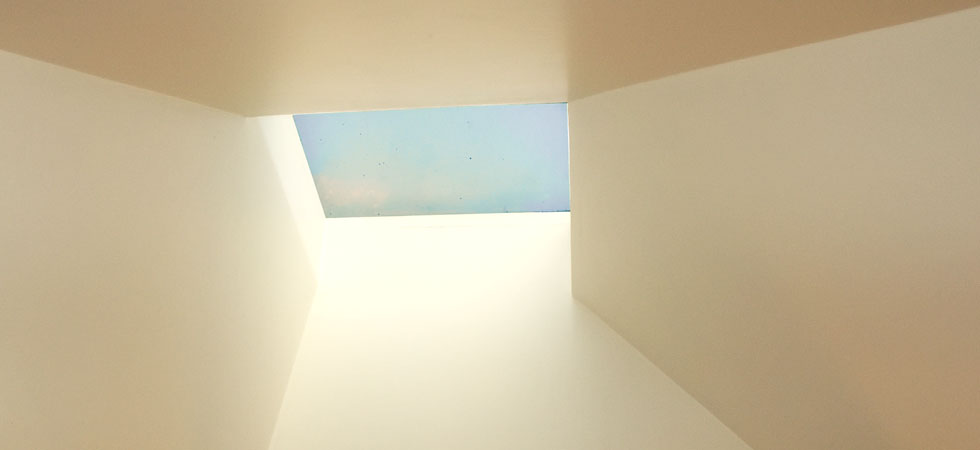 Looking up at a blu sky through an angular skylight well.