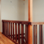An upstairs landing with wood railing, hardwood floors, and recessed lighting.