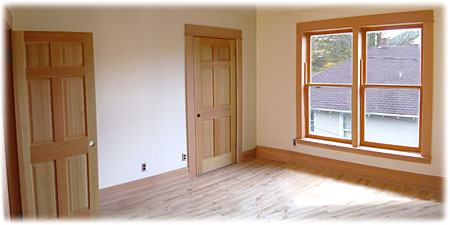 A bedroom with a walk-in closet and a large window on the second floor