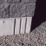 A close-up of the corner of a well-designed concrete foundation with a dark masonry block wall on top.