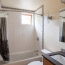 A bathroom with solid surface counter, undermount sink, and tiled shower with bathtub.